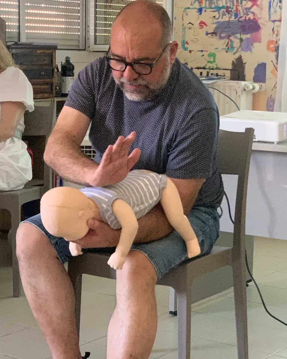 Un genitore prova la sequenza sul manichino da lattante tenuto sulle gambe